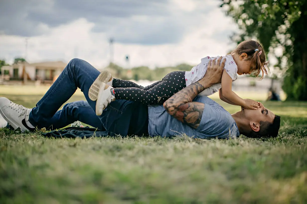 A man and his daughter are playing in the grass.