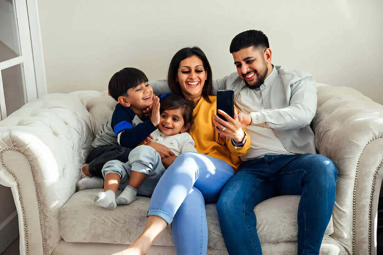 A family sitting on the couch looking at a phone