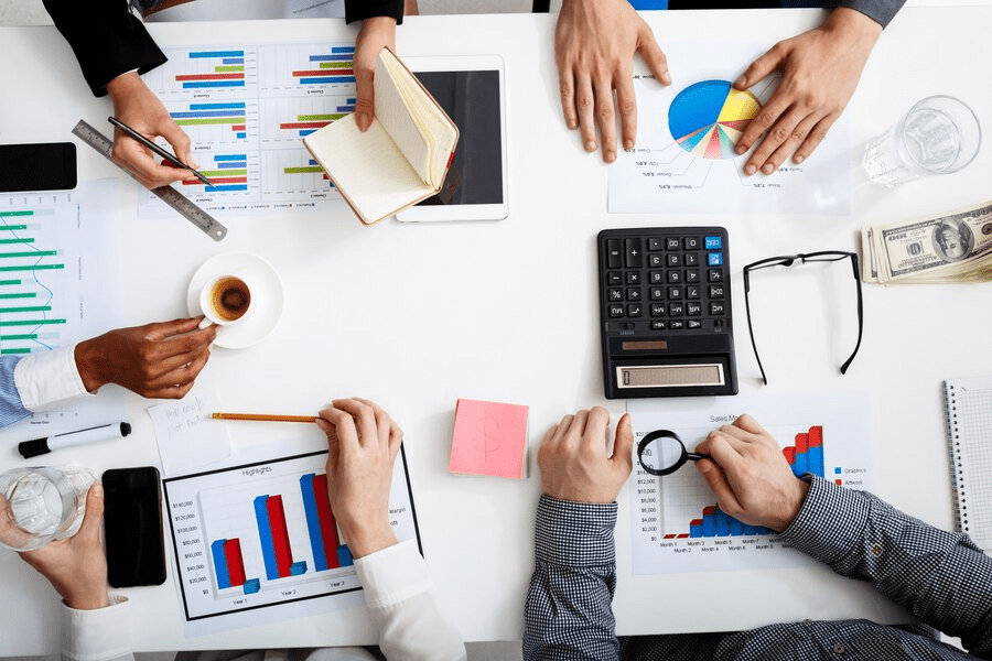 A group of people sitting around a table with papers and calculators.