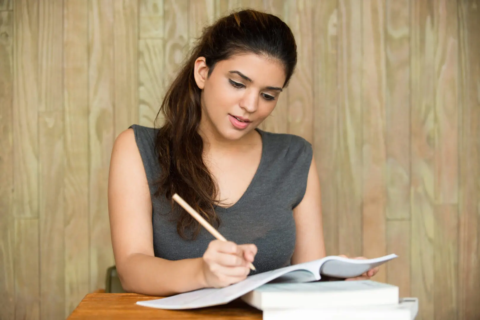 A woman is writing on paper while sitting at a table.