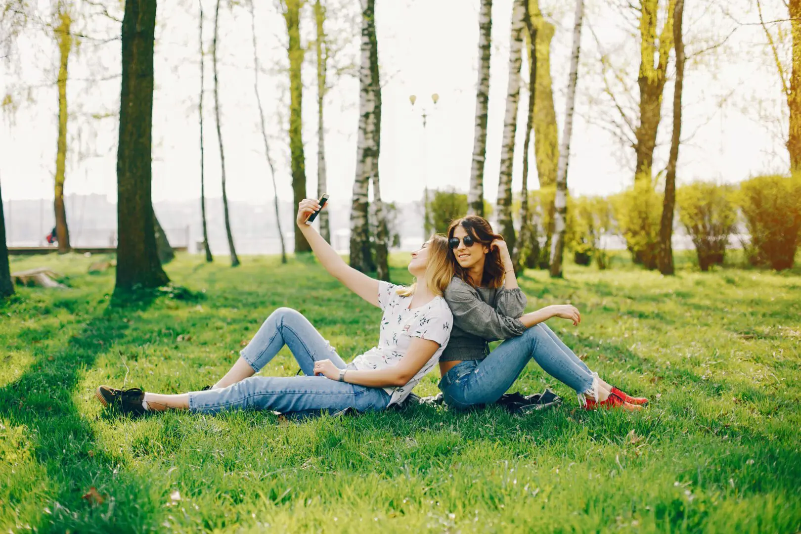 Two people sitting on the grass taking a selfie