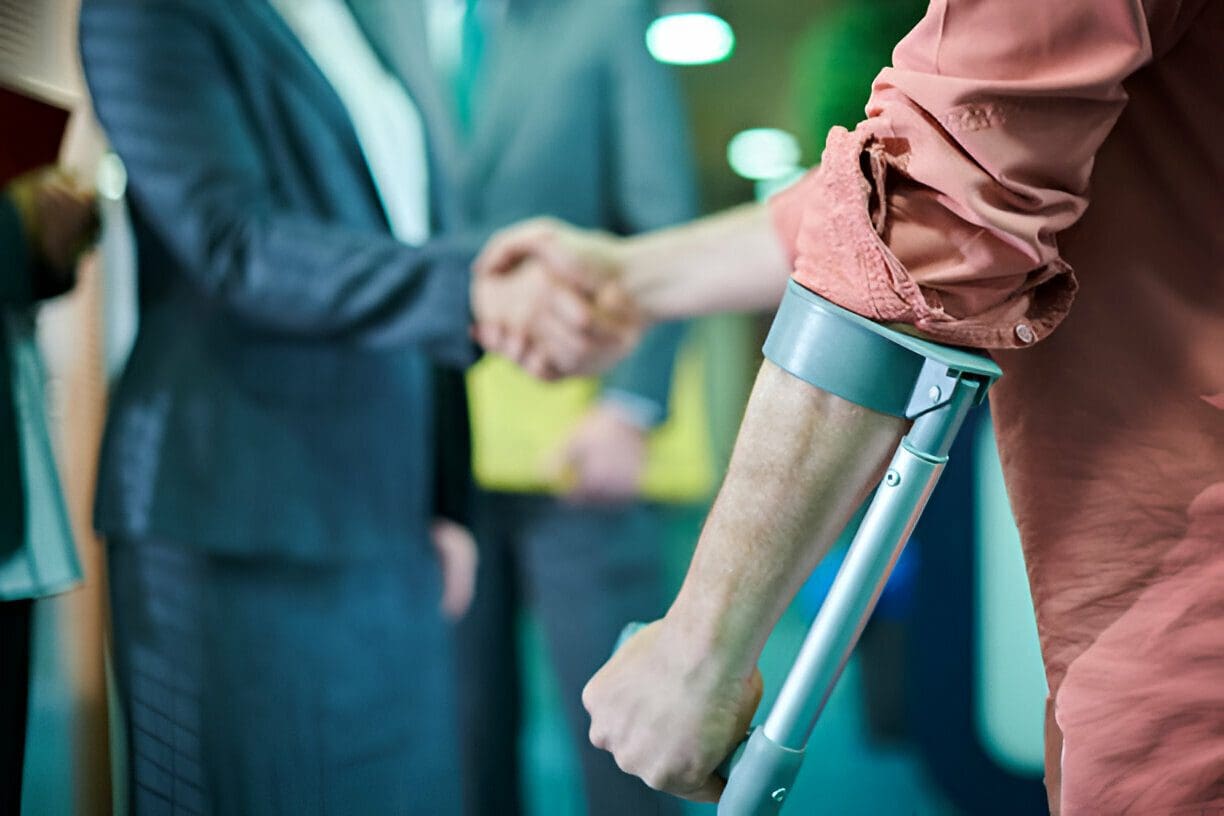 A man on crutches shakes hands with another person.