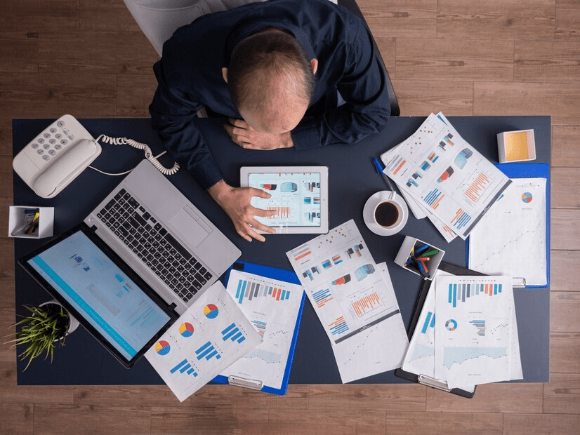 A man sitting at his desk with many papers on the table.