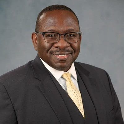 A man wearing black suit and smiling